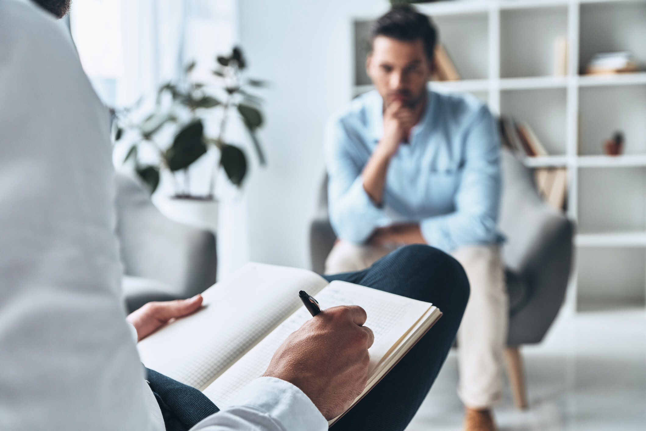 Young frustrated man solving his mental problems while having therapy session with psychologist